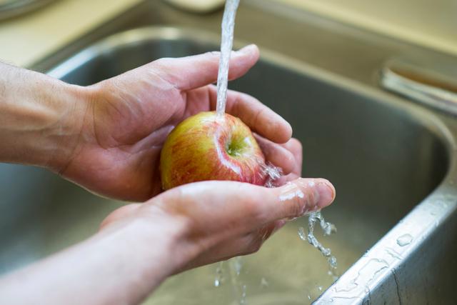 person washing an apple in the sink